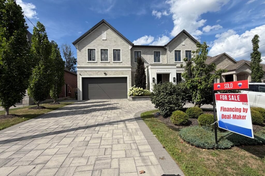 Sold real estate sign in front of a beautiful brick home, representing the return of a balanced housing market in Canada for July 2026.